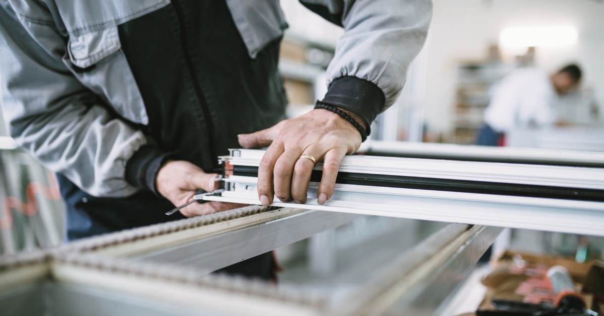 Manual worker assembling PVC doors and windows in a factory for aluminum and PVC windows and door production.