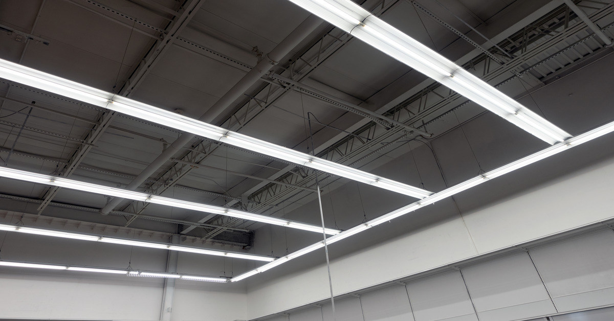 Hanging light fixtures near the roof of a commercial building. The lights are installed on an exposed ceiling.